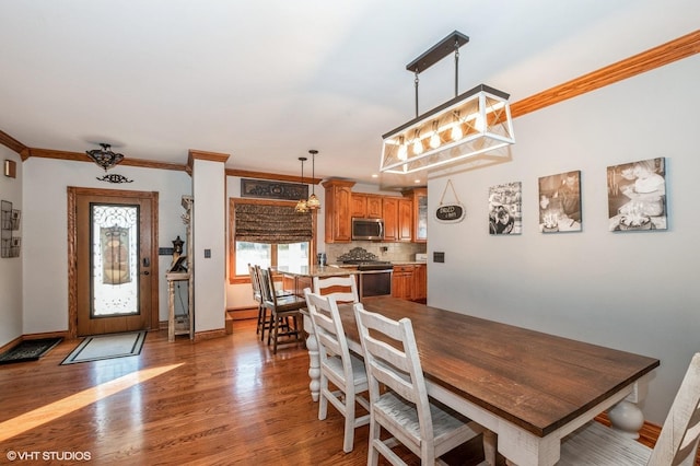 dining area with hardwood / wood-style flooring and ornamental molding