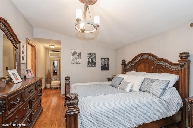 bedroom with an inviting chandelier, vaulted ceiling, a wall unit AC, and light wood-type flooring