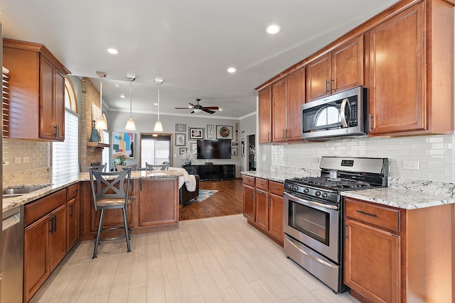 kitchen featuring decorative light fixtures, ceiling fan, kitchen peninsula, appliances with stainless steel finishes, and light stone countertops