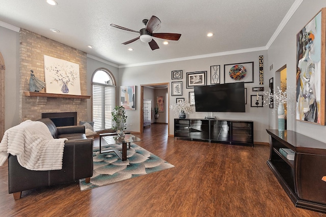 living room with a textured ceiling, ceiling fan, dark hardwood / wood-style floors, and a stone fireplace