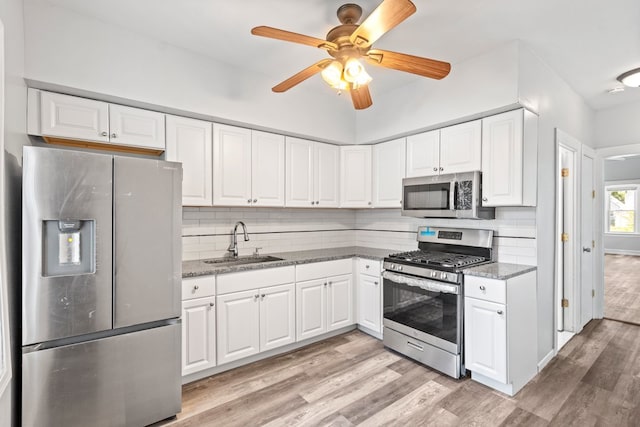 kitchen featuring tasteful backsplash, sink, white cabinets, and appliances with stainless steel finishes