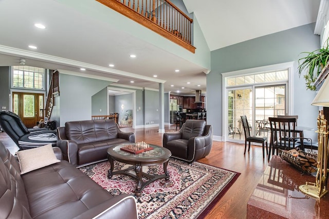 living room with hardwood / wood-style flooring, high vaulted ceiling, plenty of natural light, and ornamental molding