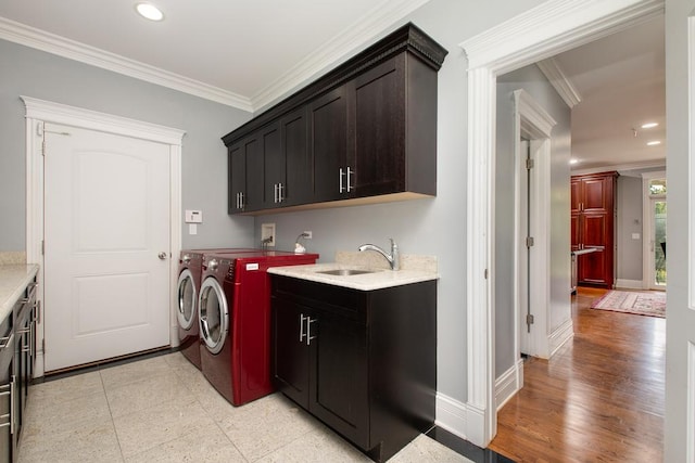 washroom featuring cabinets, ornamental molding, sink, and washing machine and clothes dryer