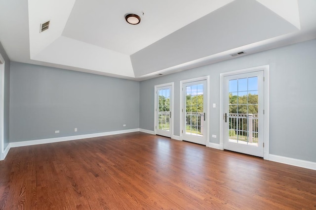 unfurnished room featuring wood-type flooring and a tray ceiling