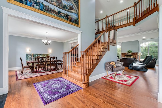 staircase with a chandelier, hardwood / wood-style flooring, and ornamental molding