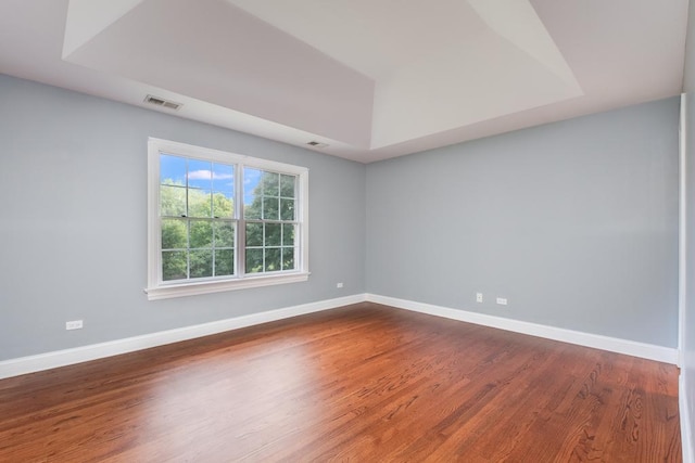 unfurnished room featuring a tray ceiling and hardwood / wood-style flooring