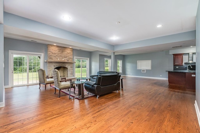 living room featuring a fireplace, light wood-type flooring, and sink