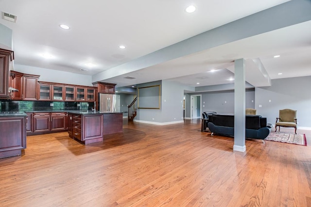 kitchen featuring light hardwood / wood-style floors, stainless steel refrigerator, tasteful backsplash, and a kitchen island