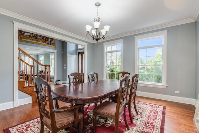 dining space with a wealth of natural light, crown molding, a chandelier, and wood-type flooring