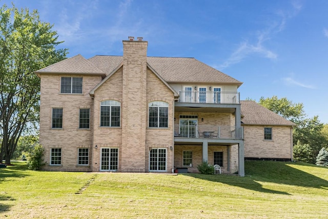 rear view of house featuring a yard and a balcony