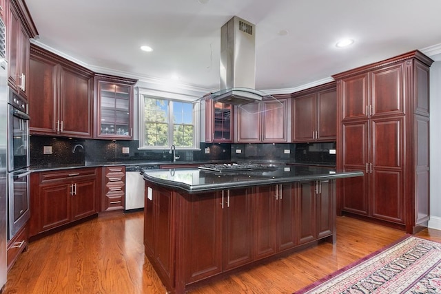 kitchen featuring stainless steel dishwasher, island range hood, gas stovetop, hardwood / wood-style floors, and a kitchen island