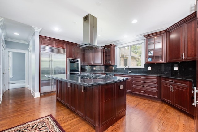 kitchen featuring a center island, backsplash, a kitchen breakfast bar, island range hood, and stainless steel appliances