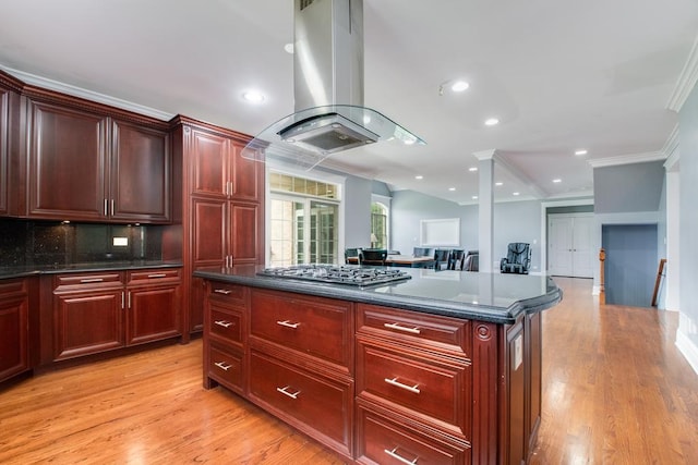 kitchen featuring island exhaust hood, decorative backsplash, ornamental molding, a center island, and stainless steel gas stovetop