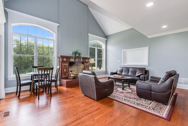 living room with hardwood / wood-style floors, vaulted ceiling, and ornamental molding