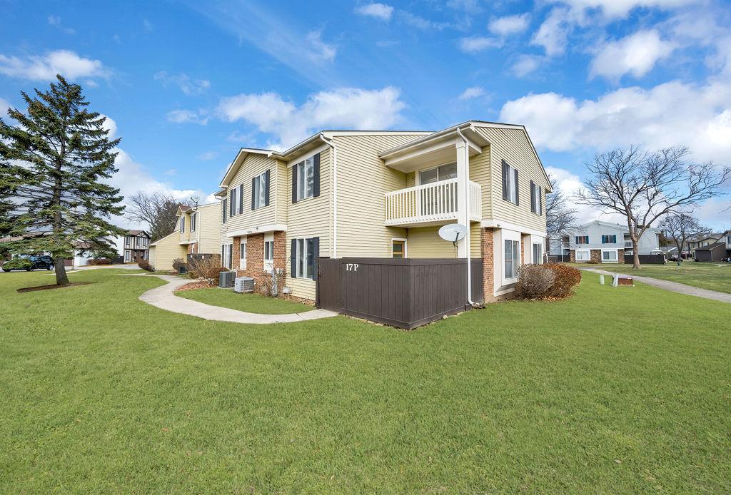 view of side of property with a lawn and cooling unit