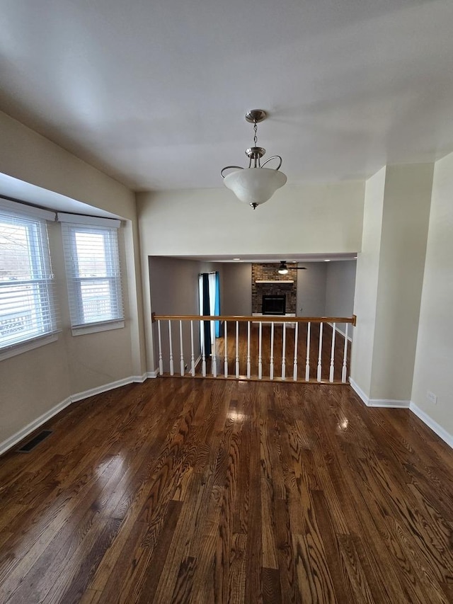 unfurnished room featuring hardwood / wood-style flooring and a brick fireplace