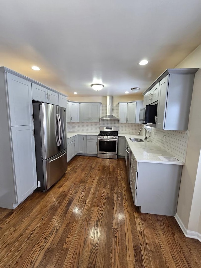 kitchen featuring sink, wall chimney exhaust hood, dark hardwood / wood-style flooring, backsplash, and appliances with stainless steel finishes