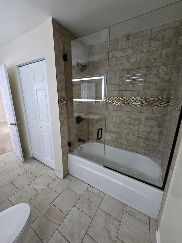 bathroom featuring tile patterned floors, toilet, and combined bath / shower with glass door