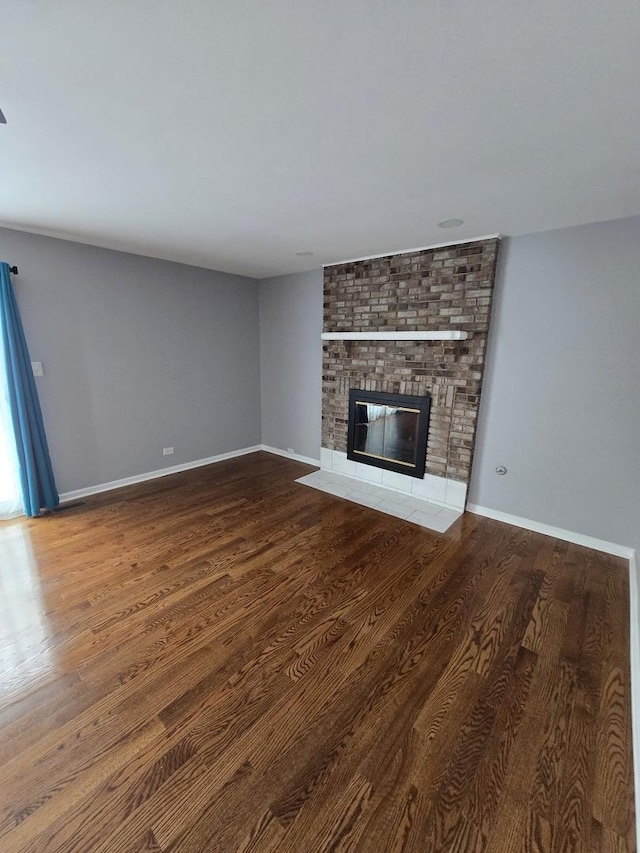 unfurnished living room featuring a brick fireplace and hardwood / wood-style flooring