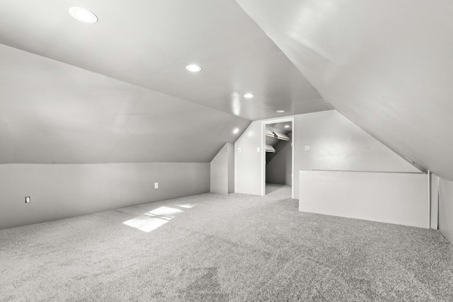 additional living space featuring light colored carpet and vaulted ceiling