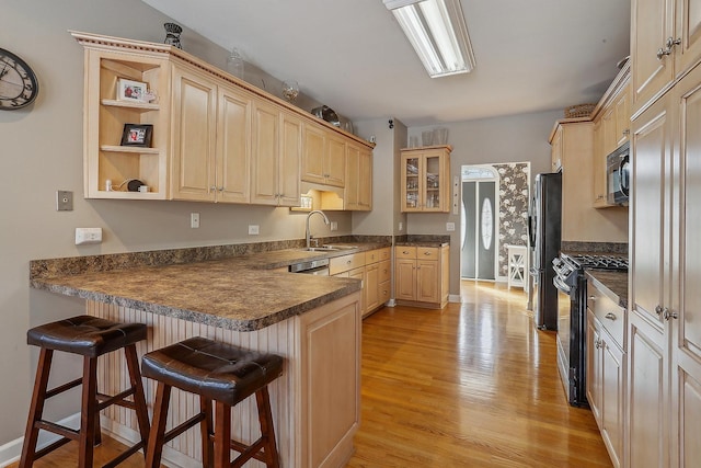 kitchen featuring kitchen peninsula, a kitchen bar, stainless steel appliances, and sink