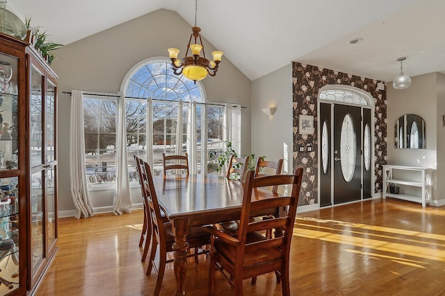 dining room with light hardwood / wood-style floors, lofted ceiling, and an inviting chandelier