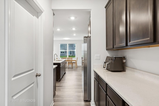 kitchen with stainless steel fridge, dark brown cabinets, light hardwood / wood-style floors, and sink