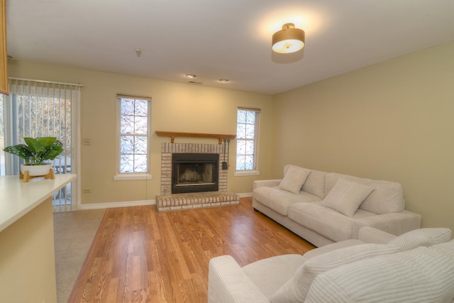 living room featuring plenty of natural light, light wood-type flooring, and a brick fireplace