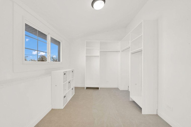 walk in closet with lofted ceiling and light carpet