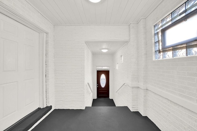 entrance foyer featuring wooden ceiling and brick wall