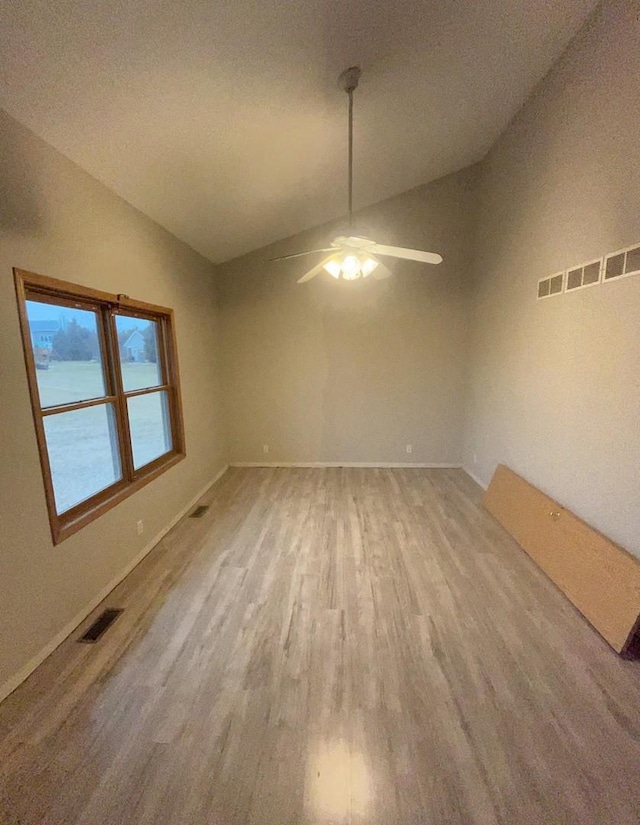 empty room with ceiling fan, a water view, light hardwood / wood-style flooring, and vaulted ceiling