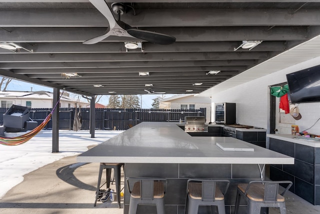 view of patio / terrace with grilling area, ceiling fan, an outdoor bar, and an outdoor kitchen