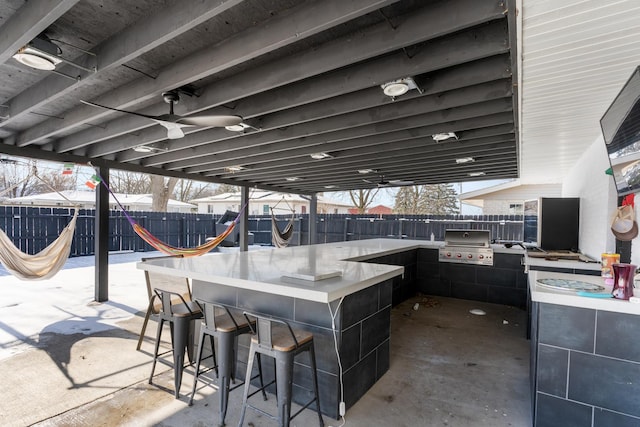 view of patio featuring a bar, a grill, ceiling fan, and exterior kitchen