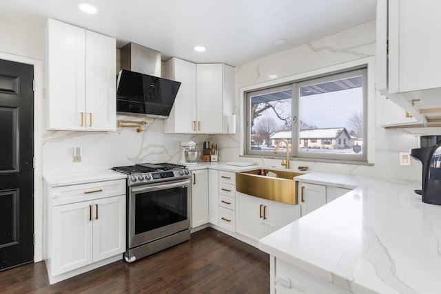 kitchen with white cabinets, wall chimney range hood, sink, gas range, and decorative backsplash