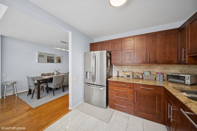 kitchen featuring appliances with stainless steel finishes, light hardwood / wood-style floors, decorative backsplash, sink, and light stone counters