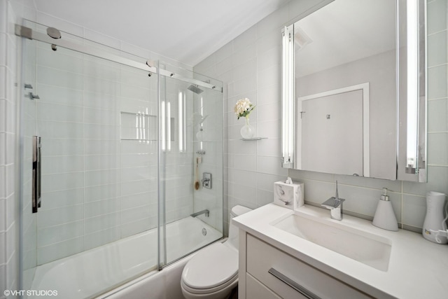 full bathroom featuring tile walls, tasteful backsplash, vanity, and shower / bath combination with glass door