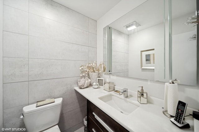 bathroom featuring toilet, tile walls, and vanity