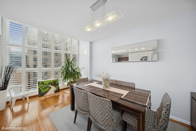 dining space featuring hardwood / wood-style floors, a wall of windows, and a healthy amount of sunlight