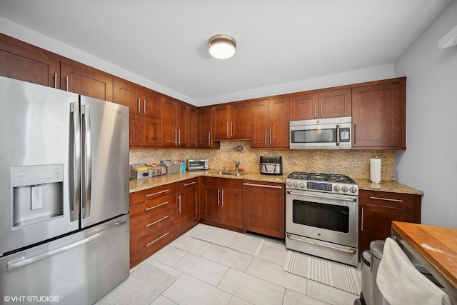 kitchen featuring light stone countertops, decorative backsplash, appliances with stainless steel finishes, and sink