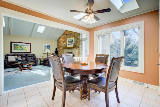 dining room with lofted ceiling with skylight, light tile patterned floors, a ceiling fan, and visible vents