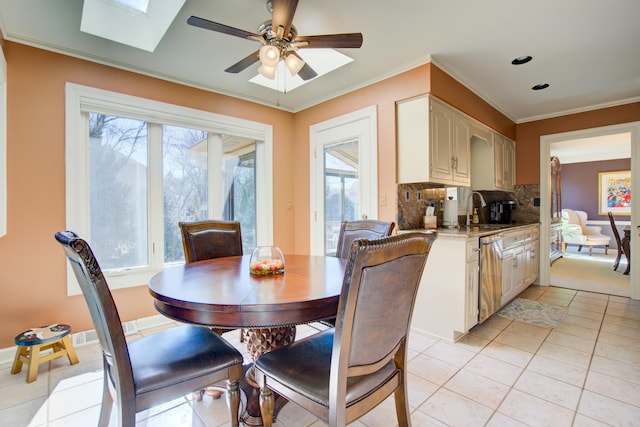 dining room with ceiling fan, plenty of natural light, a skylight, and crown molding