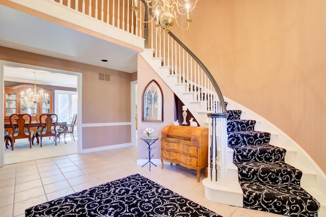 stairway featuring visible vents, a high ceiling, an inviting chandelier, tile patterned flooring, and baseboards