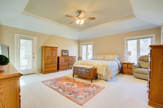 bedroom with a tray ceiling, light colored carpet, and a ceiling fan