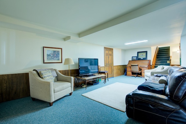 living area with carpet floors, beam ceiling, stairs, wood walls, and wainscoting