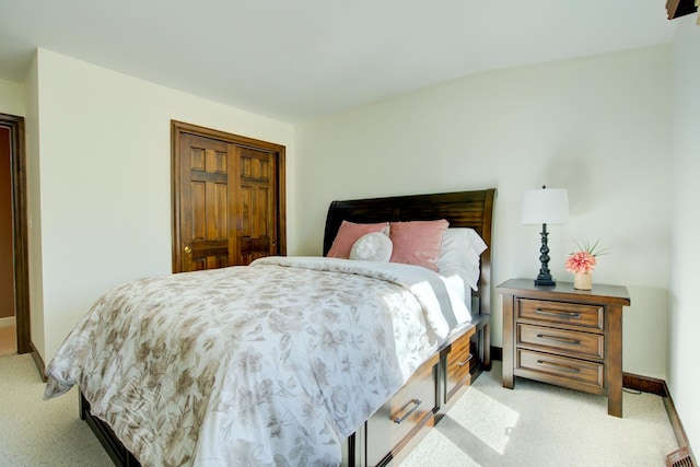 bedroom with a closet, baseboards, and light colored carpet