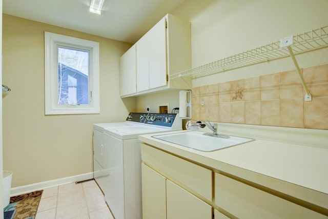 laundry room with washer and clothes dryer, a sink, cabinet space, light tile patterned flooring, and baseboards