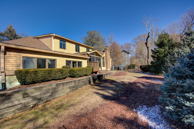 view of side of home with roof with shingles and fence