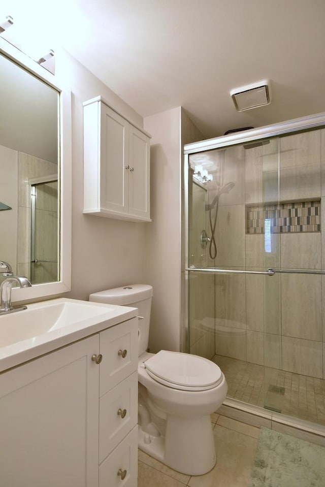 bathroom featuring vanity, toilet, a shower with shower door, and tile patterned flooring