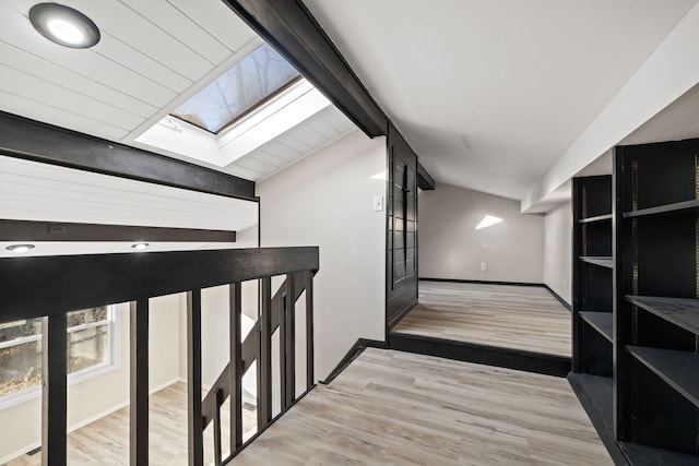 corridor featuring light hardwood / wood-style floors and lofted ceiling with skylight