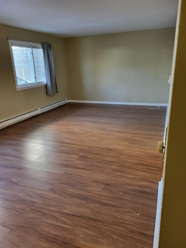 spare room with baseboard heating and hardwood / wood-style floors